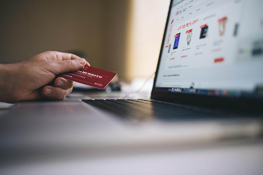 Person holding credit card near laptop