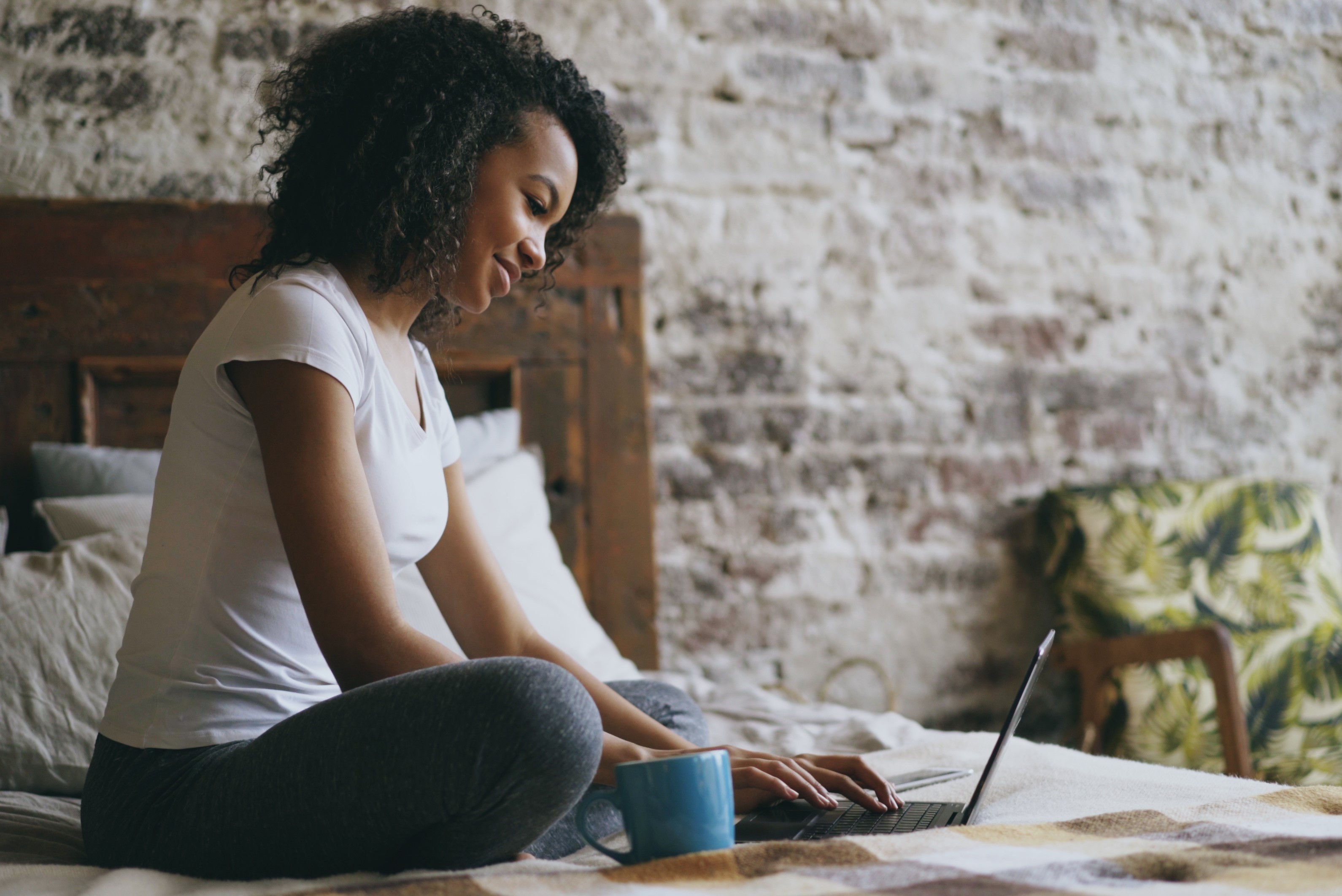 Woman sitting on bed with laptop